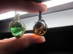 a person holding two glass pendants in their hand