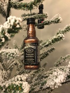 a bottle ornament hanging from the top of a christmas tree with snow on it