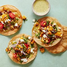 three tortillas topped with corn, tomatoes, and feta cheese next to a bowl of ranch dressing