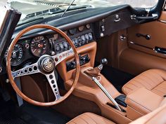 the interior of an old car with brown leather seats and steering wheel, along with dashboard controls