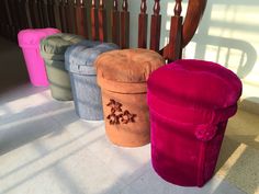 four different colored stools sitting next to each other in front of a stair case