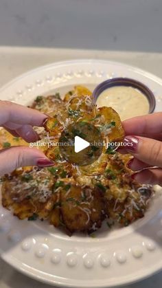 two hands reaching for some food on a white plate with sauce in the middle and another person's hand holding it