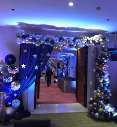 an entrance decorated with balloons and streamers for a corporate event or party, is lit up at night