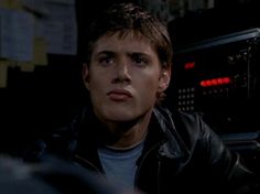 the young man is sitting in front of an old radio and looking off into the distance