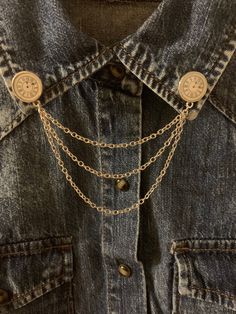 a denim jacket with gold chains attached to it