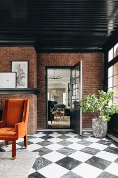 an orange chair sitting on top of a black and white checkered floor next to a brick wall