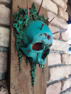 a blue skull hanging on the side of a brick building with moss growing out of it