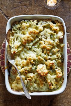 a casserole dish with broccoli and cheese in it on a wooden table