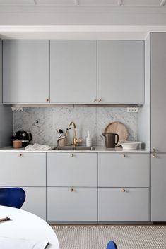 a kitchen with white cabinets and blue chairs