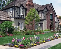 a house with many flowers in front of it and trees around the windows on both sides