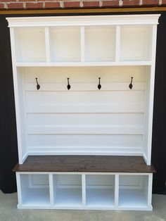 a white shelf with three hooks on it and two benches underneath the bench are empty