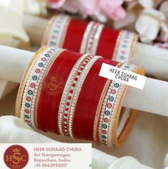 red and white bangles with gold trims on each bracelet, sitting in front of pink flowers