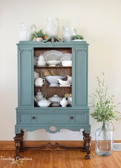 a blue china cabinet with dishes on top