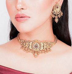 India necklace from Amrapali. This exquisite piece showcases the timeless allure of antique choker designs with a touch of Kundan jewelry elegance. Crafted with precision, it boasts intricate detailing and bears the hallmark of South India's rich jewelry tradition. This gold necklace is a testament to Amrapali's artistry in temple jewelry. Wear it to embody the grace and opulence of India's cultural heritage wherever you go. *𝐏𝐑𝐎𝐃𝐔𝐂𝐓 𝐃𝐄𝐓𝐀𝐈𝐋* * Material: Brass * Plating: Gold Plated 22k Gold Jewelry For Puja, 22k Gold Bridal Necklace For Puja, Yellow Gold Cutdana Jewelry For Navratri, Navratri Yellow Gold Jewelry With Cutdana, Yellow Gold Jewelry With Cutdana For Navratri, Elegant Navratri Jewelry With Motifs, Traditional Round Pallu Jewelry For Navratri, 22k Gold Necklaces For Navratri Celebration, Bollywood Yellow Gold Jewelry For Diwali