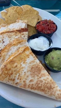 a white plate topped with quesadillas and guacamole