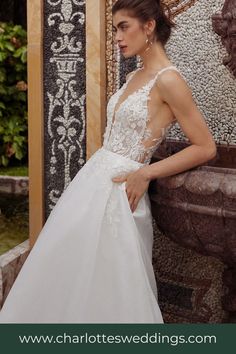 a woman in a wedding dress leaning against a wall