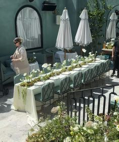 an outdoor dining area with tables covered in plants and umbrellas for people to enjoy