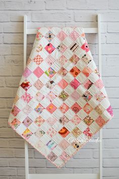 a white chair with a quilt hanging on it