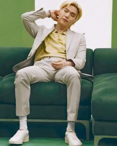 a young man sitting on top of a green couch next to a white and yellow wall