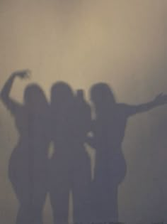 three women are standing in front of a wall with their arms spread out to the side