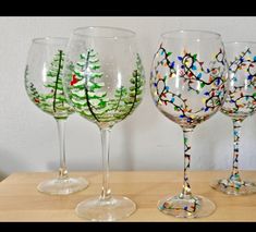 three wine glasses with christmas trees painted on them