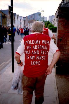 an older man is walking down the street with his back turned to the camera and has a message written on it