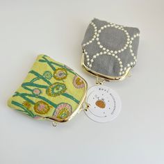 two purses sitting next to each other on top of a white table with a tag