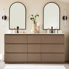 a bathroom with three mirrors and two vases on the counter top, next to each other