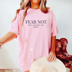 a woman wearing a pink shirt that says fear not, for i am with you