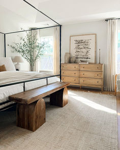 a bedroom with a bed, dresser and bench in the middle of it on carpeted flooring