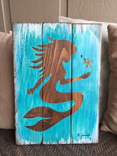 a wooden sign with an image of a mermaid sitting on it's back legs