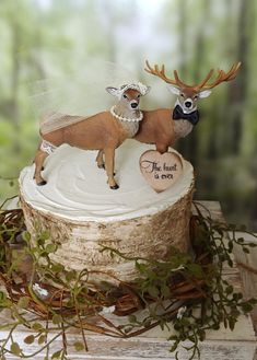 two deer figurines sitting on top of a cake