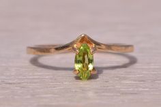 This stunning piece, known as The Verdant Glow, features a captivating marquise-cut peridot at its center, exuding a vibrant green hue. The peridot is elegantly set in a yellow gold band, creating a sleek and modern design that enhances the gem's natural beauty. This exquisite ring is currently a finger size 6 yet can be adjusted to any finger size for an additional charge upon request, ensuring a perfect fit. Love this piece, but don't have the money to spend right now? We offer FREE layaway on every item in our shop. With just 20% down, take one full year (interest-free) to pay off your new jewelry! There are no hidden fees or charges, ever. For more information on our layaway policy, please contact us. Each piece has been hand-selected and meticulously identified and graded by a Graduat Peridot Ring, Vibrant Green, Marquise Cut, Gold Band, The Money, Rings Statement, Gold Bands, Statement Rings, Natural Beauty