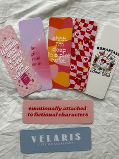 four bookmarks with different sayings on them sitting on a white sheeted surface