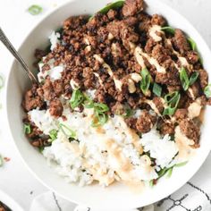 a white bowl filled with rice and ground beef on top of a patterned table cloth