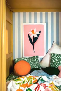 a bed with colorful pillows and a painting on the wall