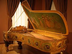 an ornately painted grand piano sits in the middle of a room