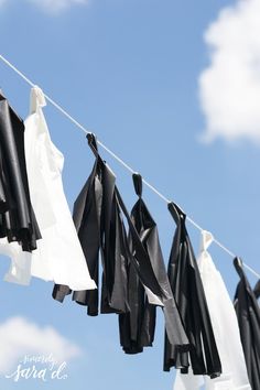 black and white clothes hanging on a line with clouds in the sky behind them,