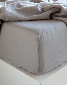 an unmade bed with grey linens on it