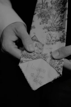 two hands holding a piece of cloth with writing on it