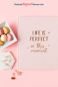 a notebook with the words life is perfect in this moment next to some macaroons