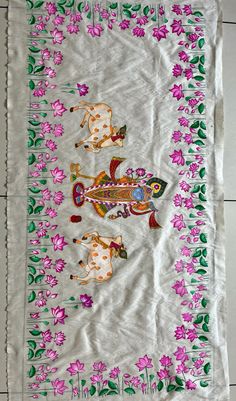 an embroidered table cloth with horses and flowers on it's edges, hanging from a tile floor