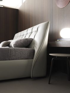 a white leather couch sitting next to a table with a lamp on top of it