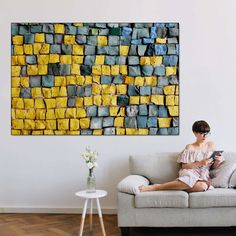 a woman sitting on top of a couch next to a wall covered in yellow and blue blocks