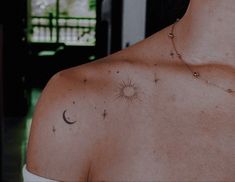 the back of a woman's shoulder with stars and a sun tattoo on it