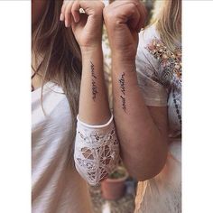 two women with matching tattoos on their arms, one is holding the other's hand