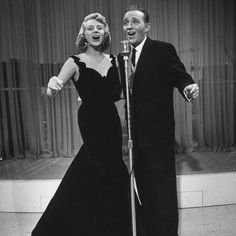 two people standing next to each other in front of a microphone and wearing formal clothes