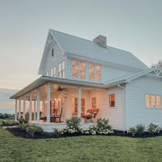 a white house with lots of windows on the front and side of it, surrounded by grass