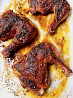 three pieces of meat sitting on top of a pan covered in mustard and seasoning