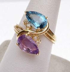 This is a nice, symmetrical freeform ring from the 1980s. The ring has a pear cut amethyst and a pear step cut synthetic blue topaz that measure 9 x 6 mm each. The ring also has 4 full cut round diamonds that have a combined weight of 0.04 carats in all. Diamonds have SI2 clarity and H color. The band has grooves etched in so it looks like 3 bands put together and there is an S shaped piece that connects between the two pear shaped stones. The ring is stamped 14kt and weighs 3.9 grams. The ring Feminine Rings, Mother's Rings, Twisted Wire Rings, Styled Jewelry, Rings Amethyst, Dream Inspiration, Freeform Ring, Engagement Rings Couple, Lucid Dream